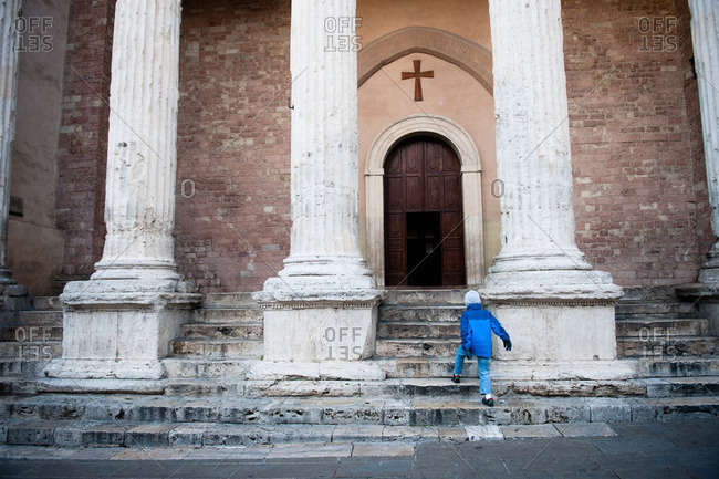 Boy walking up to Temple of Minerva in Assisi, Italy
