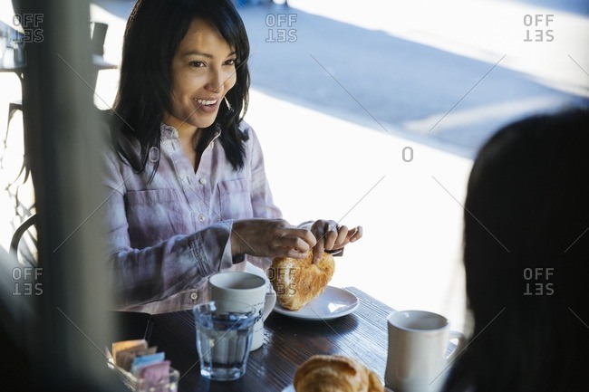 Two women having coffee and croissants at an outdoor cafe