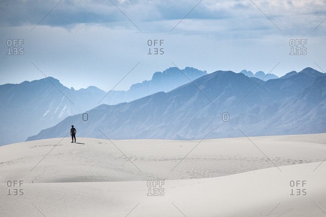 Man standing on a sand dune towards San Andres Mountains at White Sands National Monument