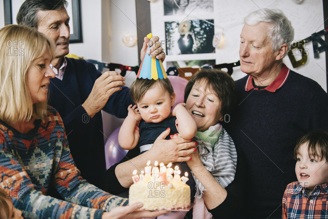 A family gathered to celebrate a one year old girl\'s birthday party A cake with lots of candles