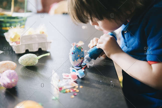A child decorating eggs at Easter with glitter, glue and paint
