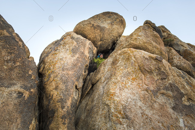 ALABAMA HILLS, LONE PINE, CA, USA A 30 year-old woman peers out from a crack in a stack of boulders