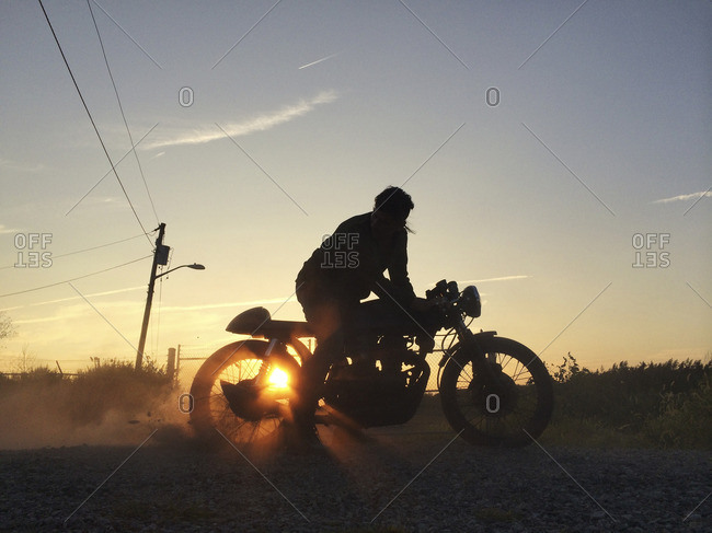 Silhouette of man riding motorcycle against sky