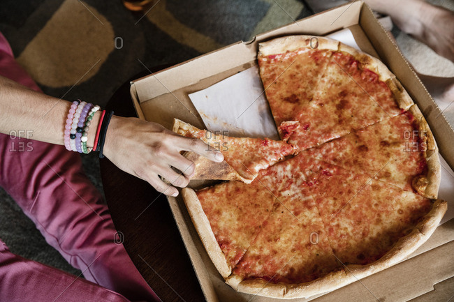 Cropped image of hand holding pizza slice at home