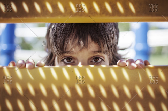 Portrait of boy peeking through outdoor play equipment