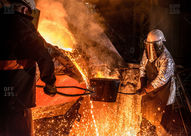 Workers pouring molten metal in foundry
