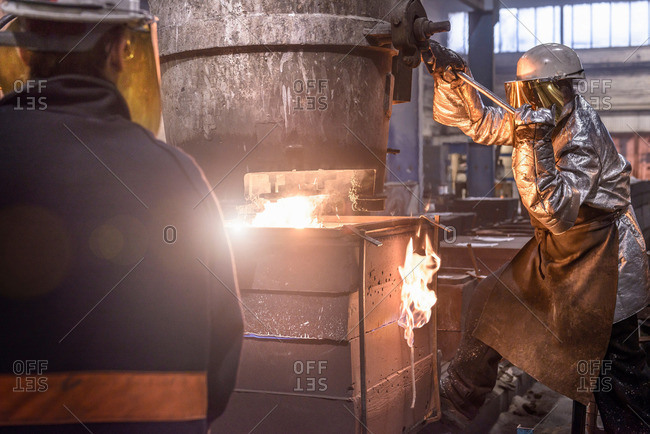 Workers pouring molten metal into molds in foundry