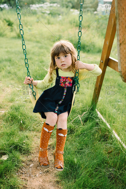Little girl wearing socks and sandals on a swing