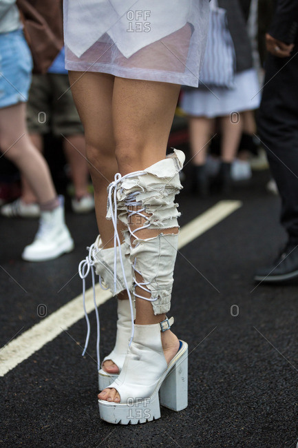 Woman wearing white platform sandals with torn jean leg warmers