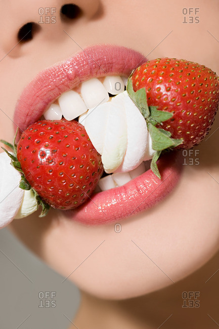 Young woman biting strawberries and marshmallows