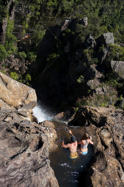 Man and woman in rock pool at waterfall