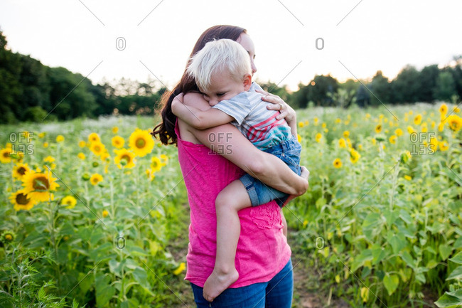Boy hugging woman among sunflowers
