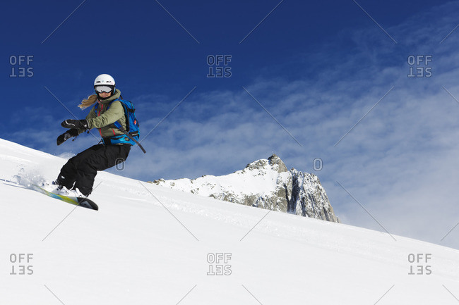Switzerland, Andermatt, Young woman snowboarding in Alps