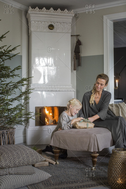 Sweden, Mother and daughter sitting by fireplace opening Christmas presents