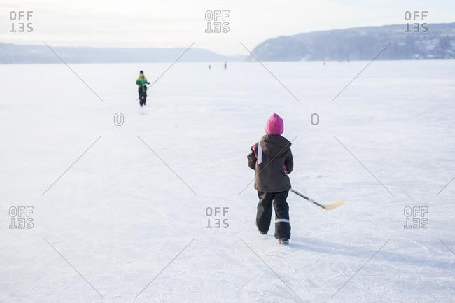 Sweden, Vastergotland, Lerum, Lake Aspen, Siblings playing ice hockey on lake
