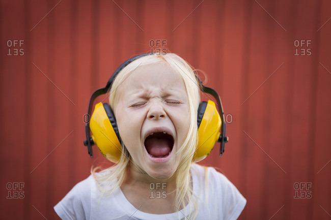 Sweden, Narke, Filipshyttan, Portrait of blonde girl wearing ear muffs, screaming with eyes closed
