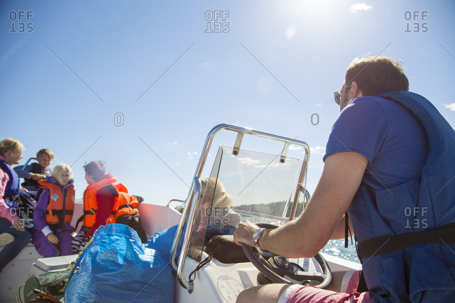 Sweden, Swedish West Coast, Holland, Kungsbackafjorden, Man with kids (6-7, 8-9, 10-11) on motor boat