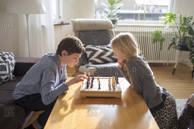 Sweden, Boy and girl playing chess in living room