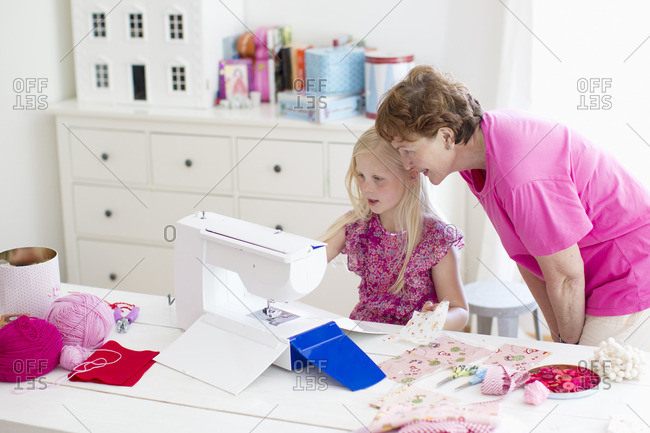 Finland, Grandmother with granddaughter playing with sewing machine
