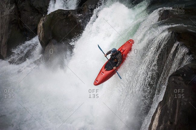 Man kayaking down a waterfall