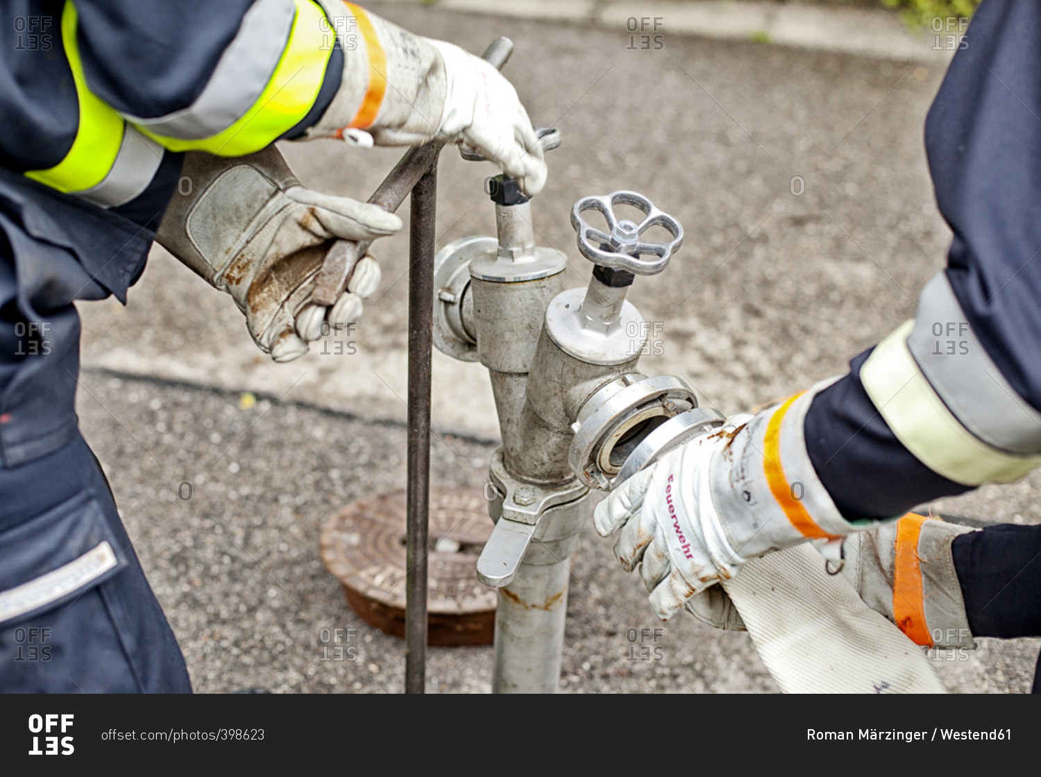 Close Up Of Firefighters Connecting Hose To Fire Hydrant Stock Photo