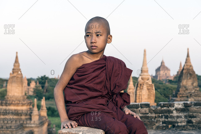 Young Buddhist monk, sitting on an ancient temple top