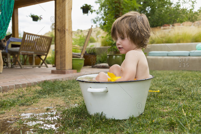 Toddler boy playing in a bucket of water