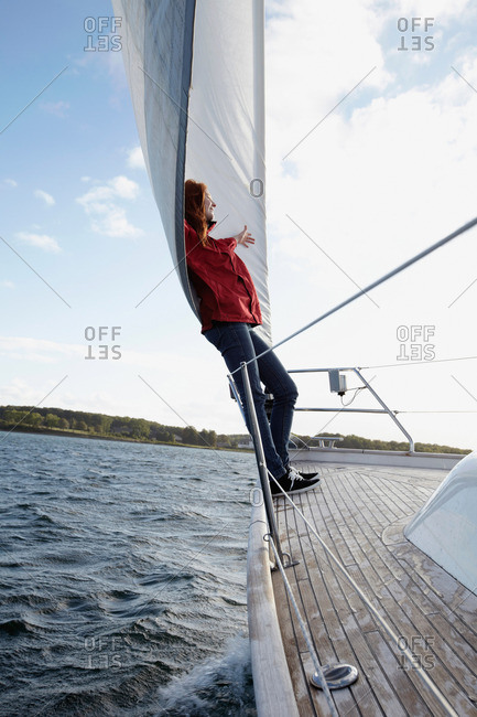 Woman leaning against sail on yacht