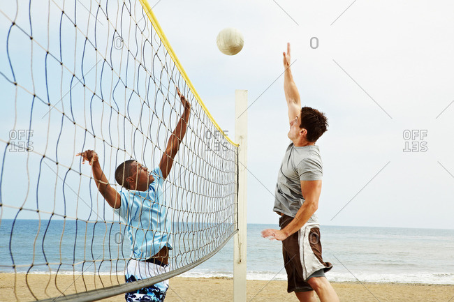 Two young men playing beach volleyball