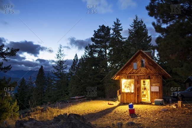 Illuminated wooden cabin in forest at night