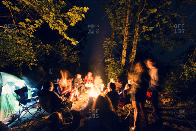 Friends sitting around campfire in forest