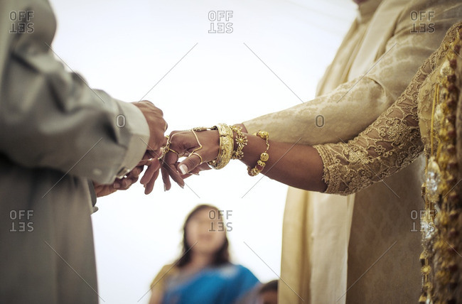 Priest tying fingers of bride and groom during wedding ceremony