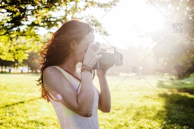 Side view of woman photographing through retro styled camera