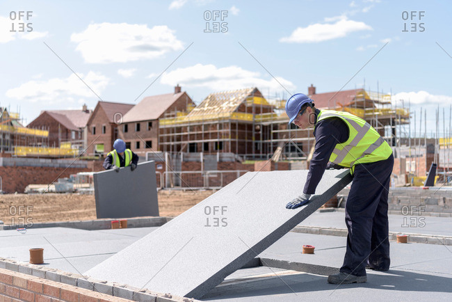 Builders laying insulation on housing building site