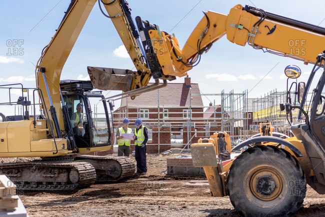 Builders with machinery on housing building site
