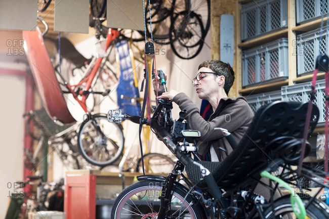 Woman in bicycle workshop repairing recumbent bicycle