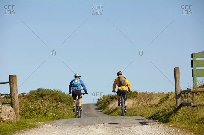 Back view of cyclists cycling on rural road