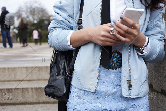 Mid section of woman wearing pastel blue using smartphone