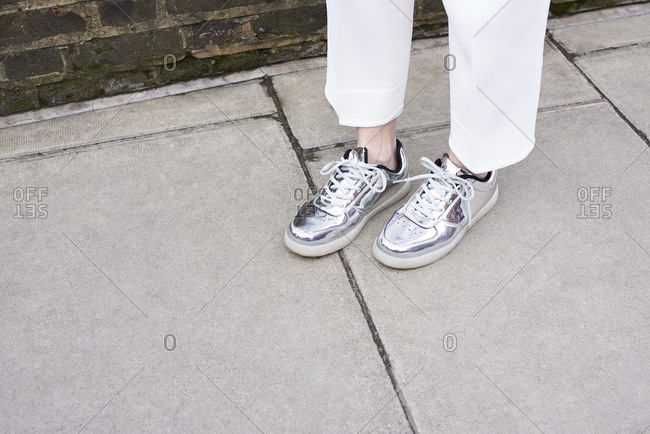 Woman standing in street wearing silver shoes, detail