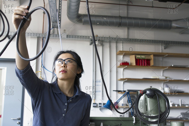 Young female engineer checking cables in an industrial plant
