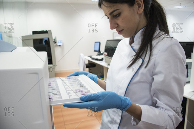 Laboratory technician in analytical laboratory putting object plates in cytology reader