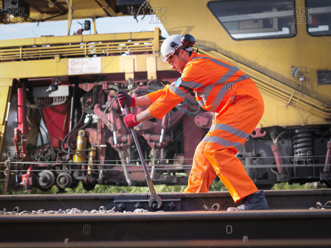 Railway maintenance worker tightening bolts on track
