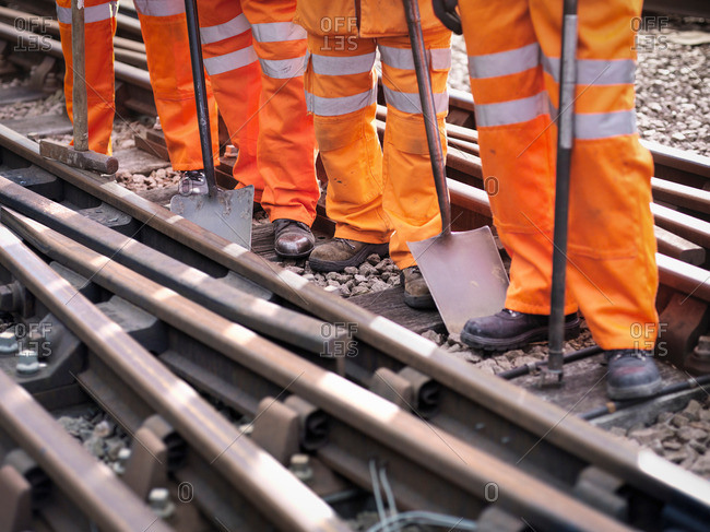 Railway maintenance workers standing with tools on track, low section