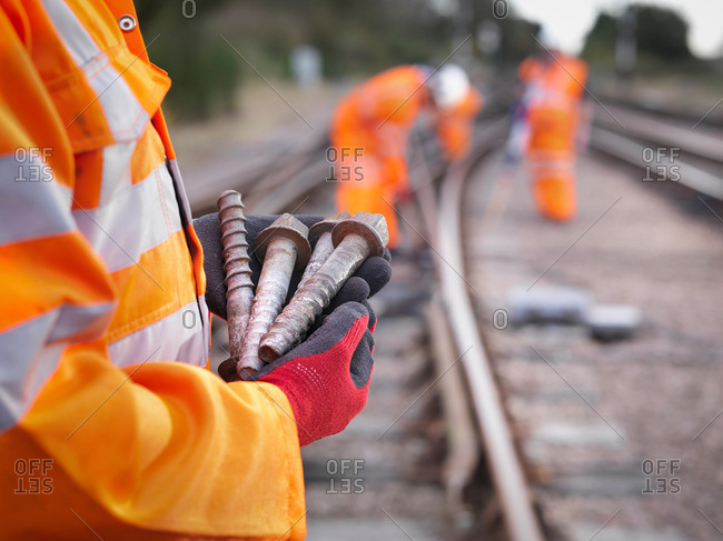 Railway maintenance worker holding track screws, close up