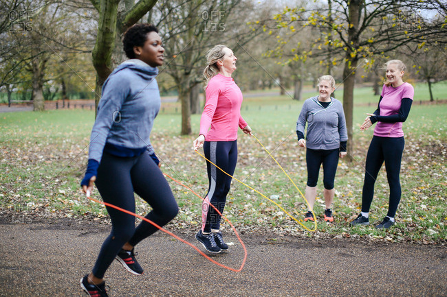 Women and teenager competing with skipping rope in park