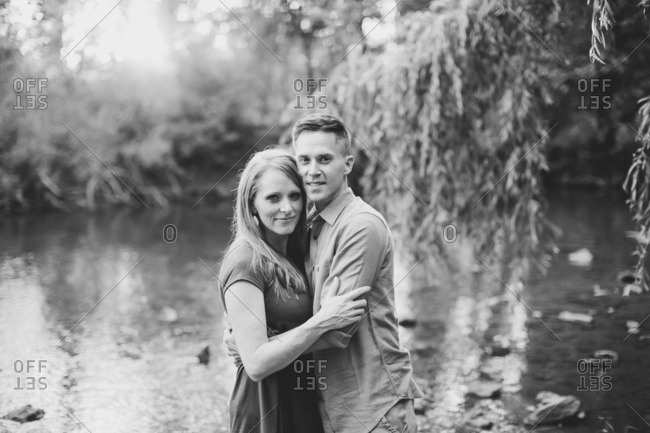 Couple embraced beside a river in black and white