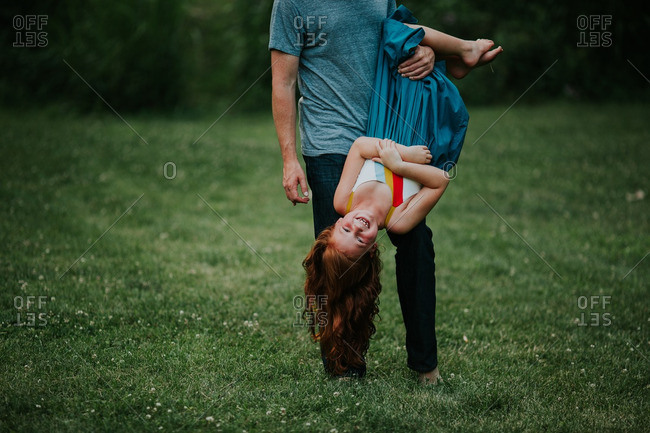 Father holding his redhead daughter upside down