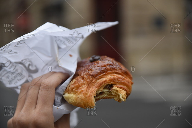 Close-up of a person holding a pastry with a bite missing