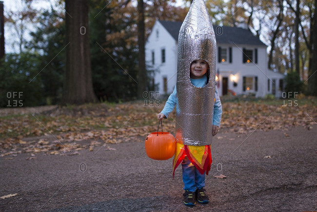 Boy standing on a suburban street wearing a rocket Halloween costume