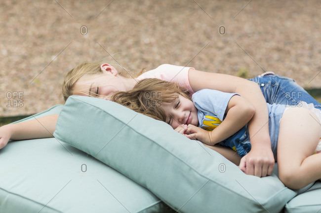 Children resting outside on a pile of cushions